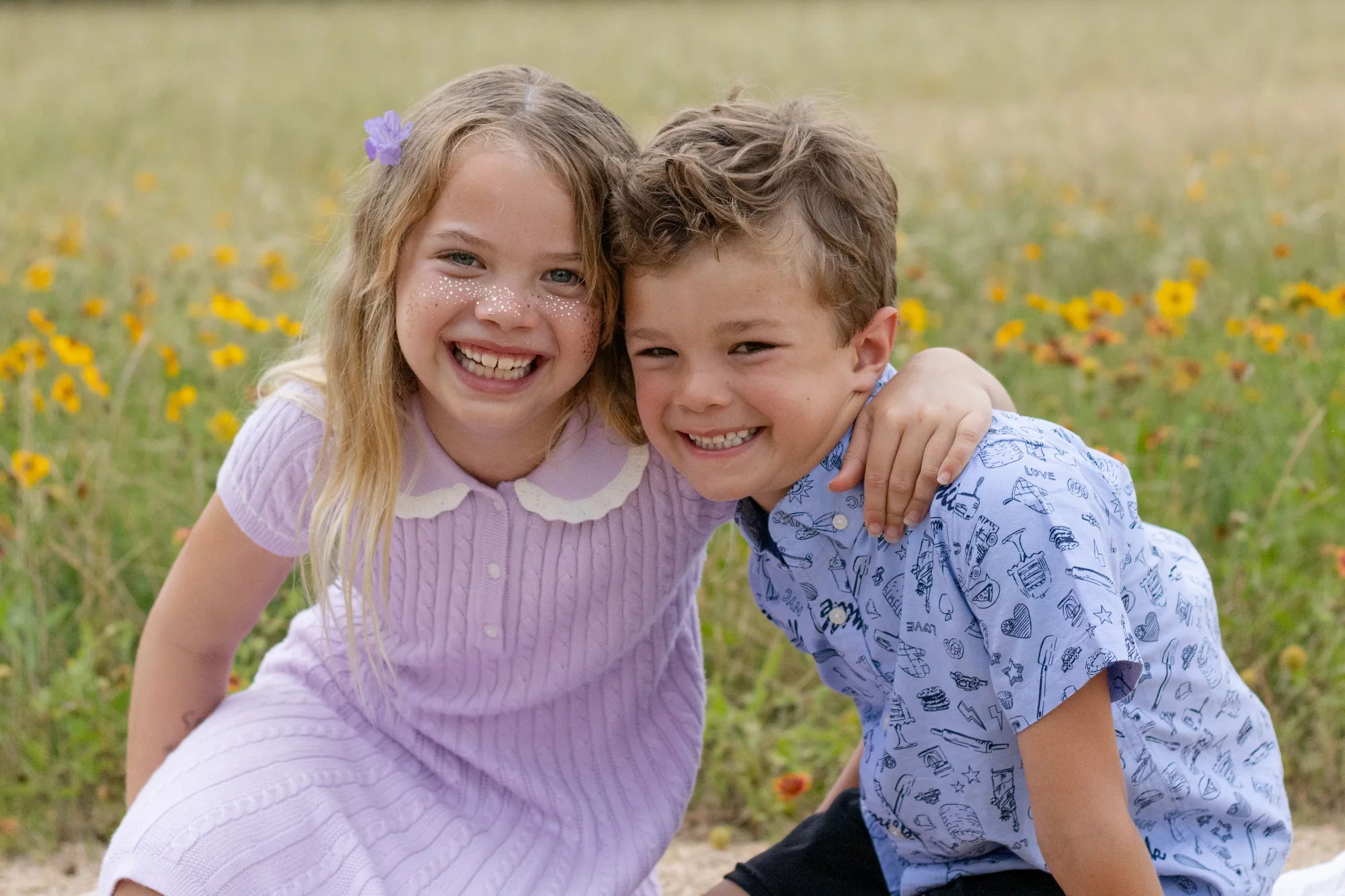 Two smiling children together in a field of wildflowers