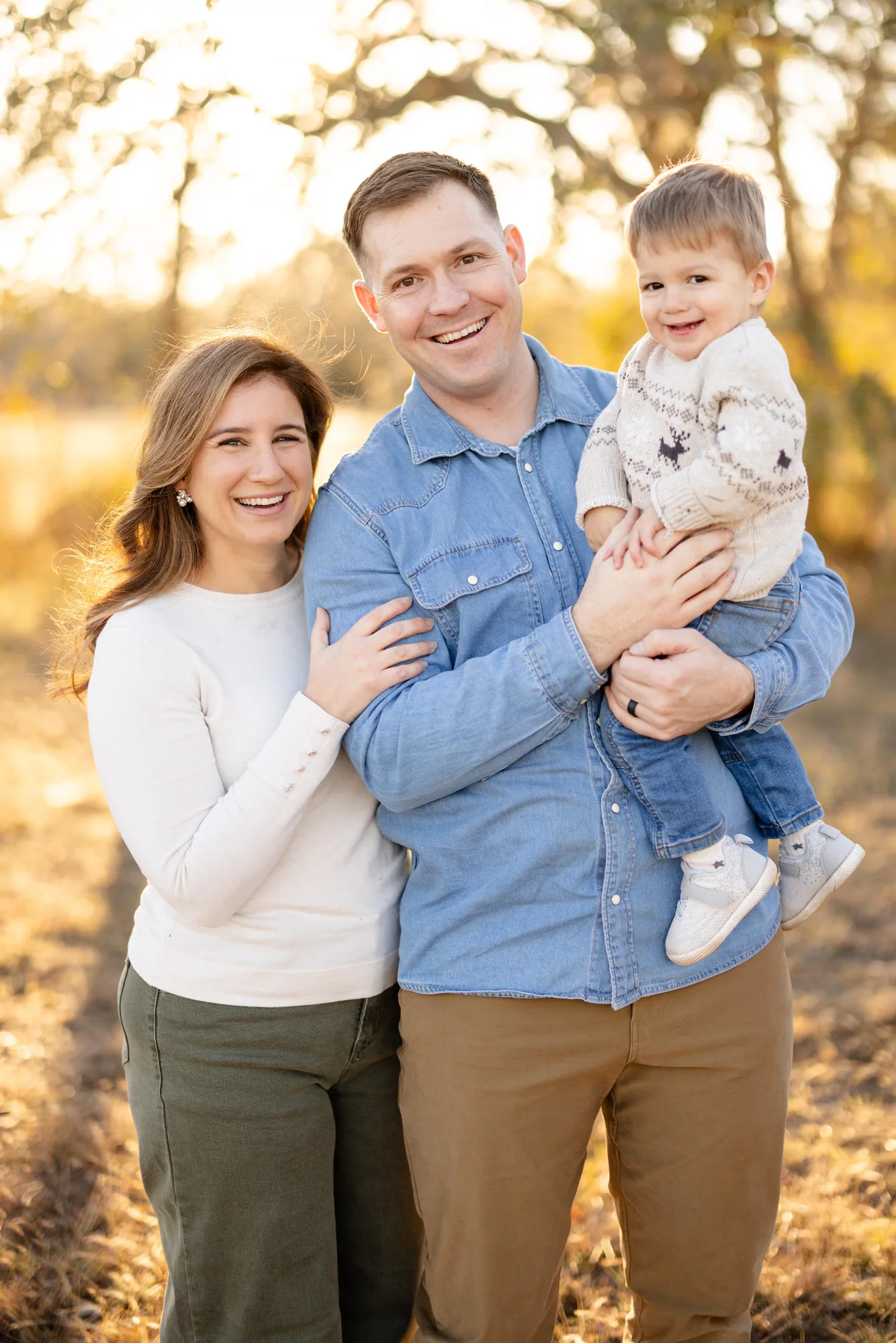 Lindsey smiling outdoors with her husband and young son
