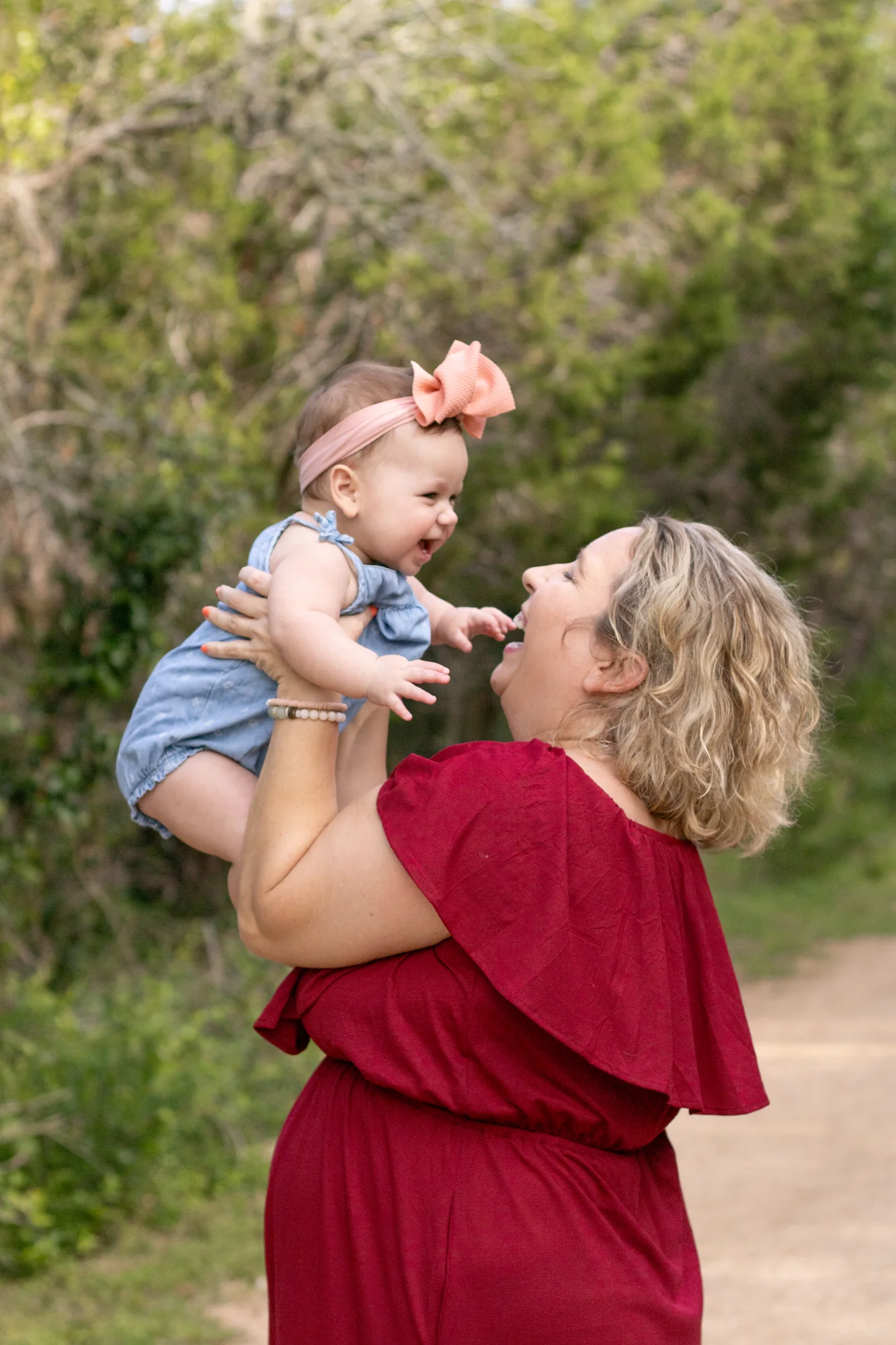 A mother lifting her smiling baby outdoors